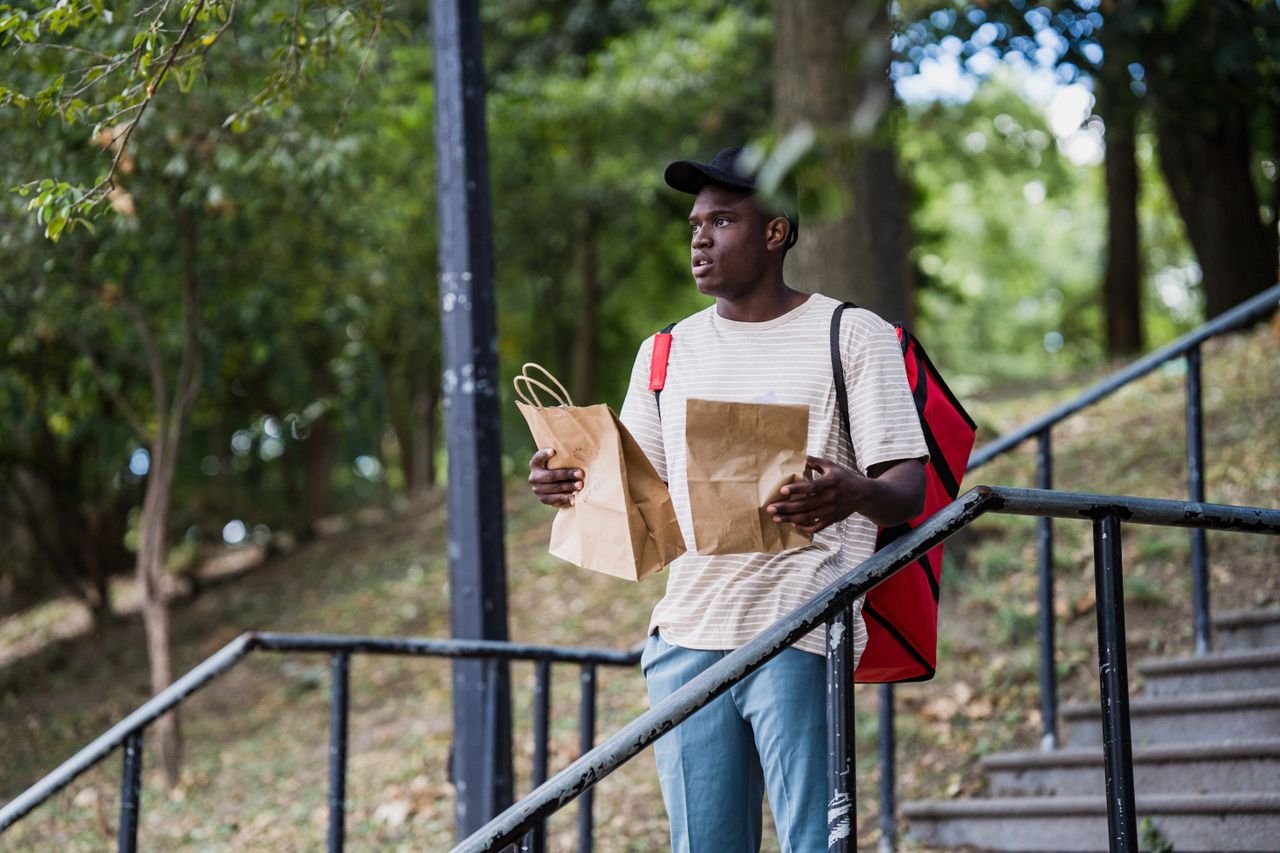 The Art of Drawing Readers In: Your attractive post title goes here Young man delivering packages outdoors, standing on stairs with trees around.